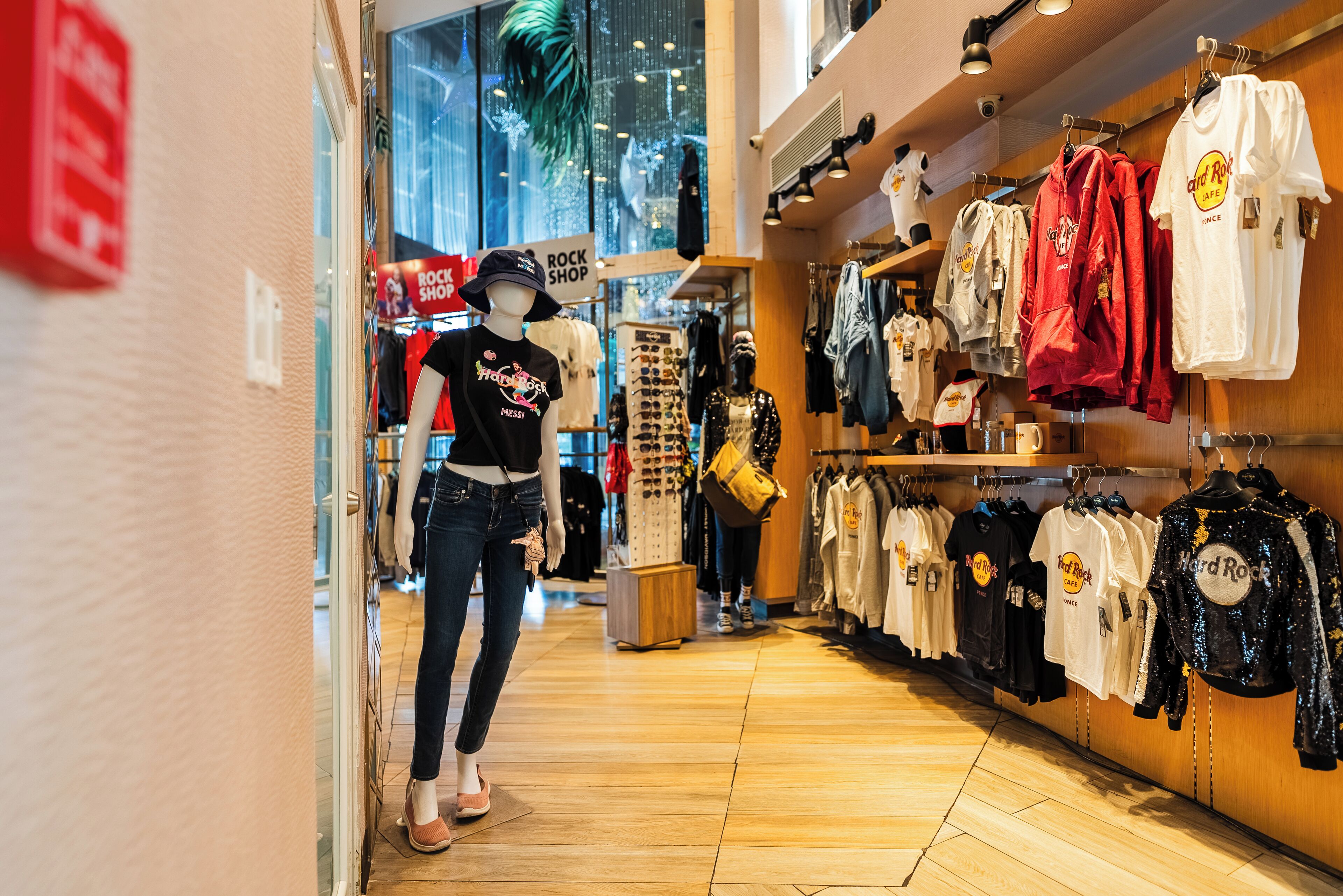 A clothing store with racks of clothes and a mannequin in the center.