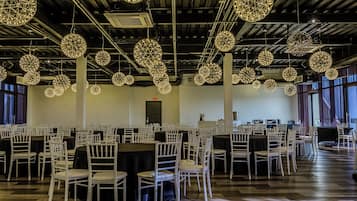 A spacious hall with round tables and chairs, large hanging spherical light fixtures, and a high ceiling with visible ductwork.