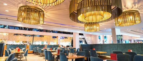Un restaurante moderno con varias zonas de estar, incluyendo reservados y mesas.