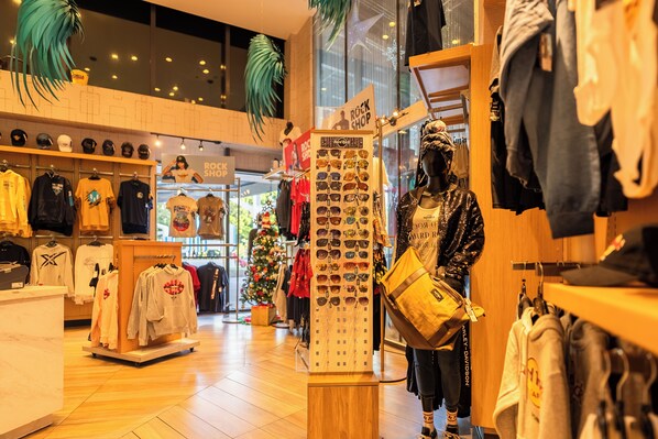 A clothing store with a mannequin displaying a yellow bag and various clothing items on racks.
