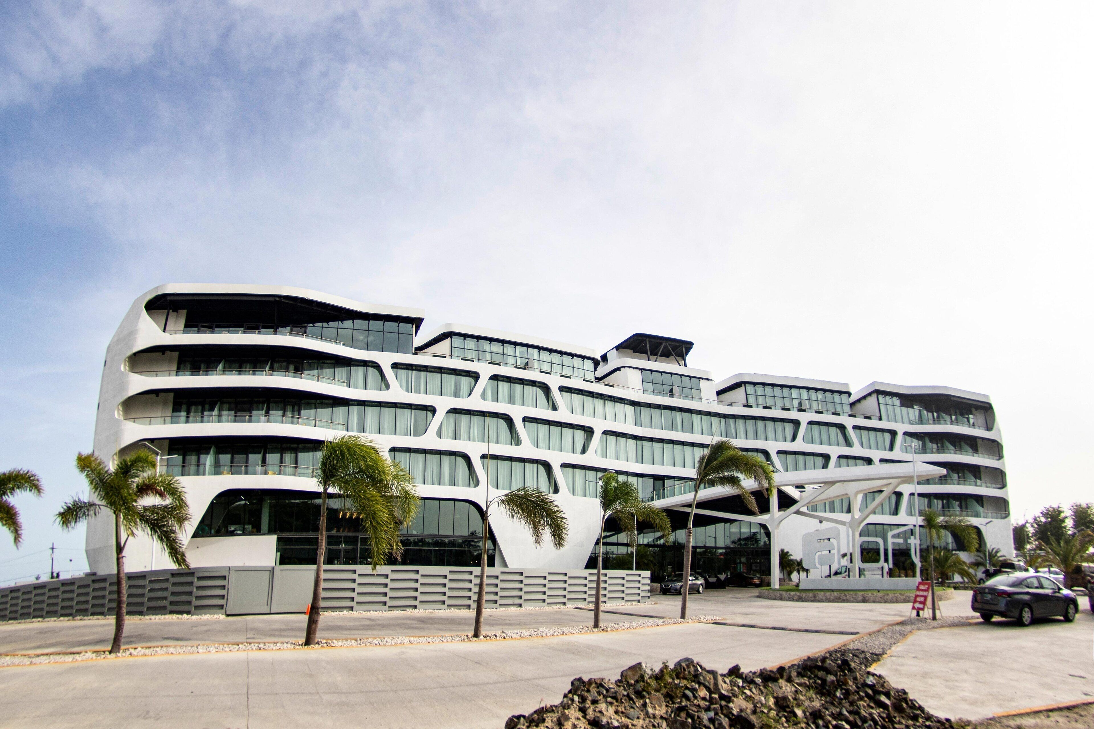 A modern multi-story building with a unique curved architecture, featuring balconies and large windows.
