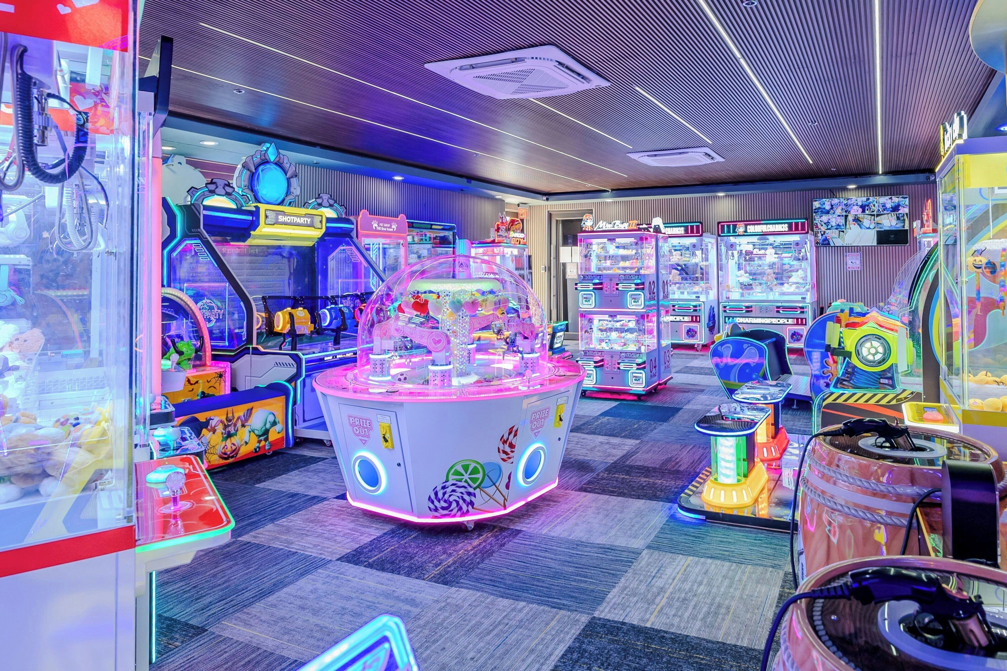 A brightly lit arcade with various claw machines and gaming machines.