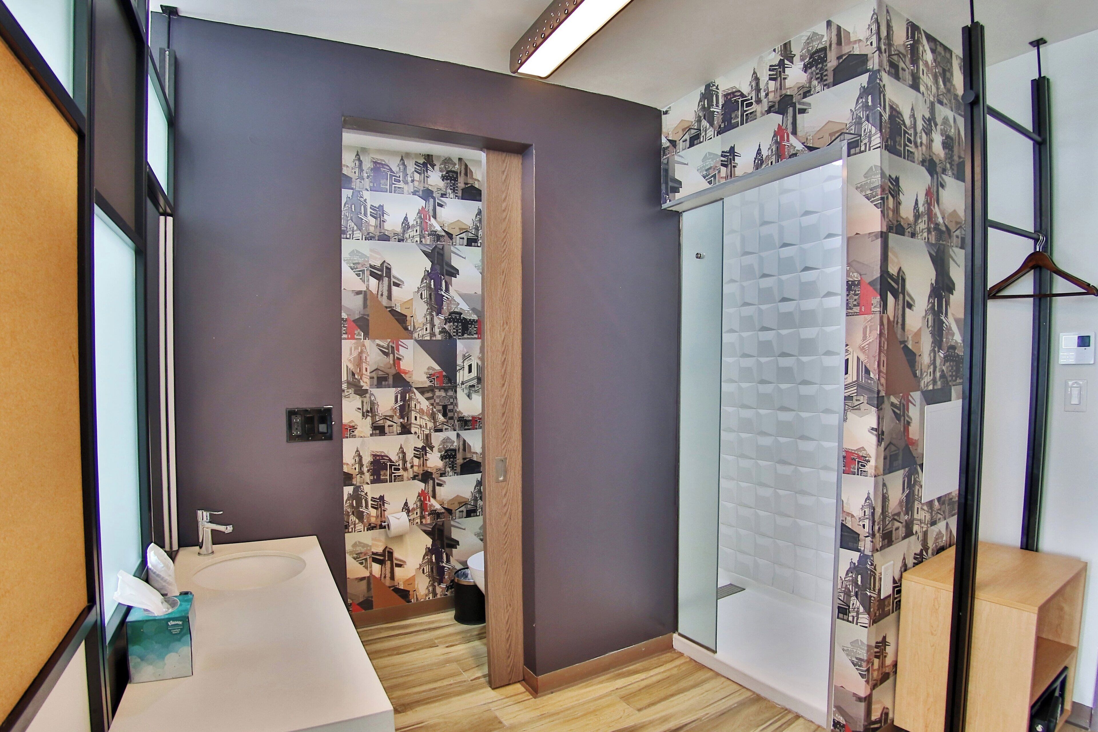 Un baño moderno con un espejo grande, un lavabo y una zona de ducha.