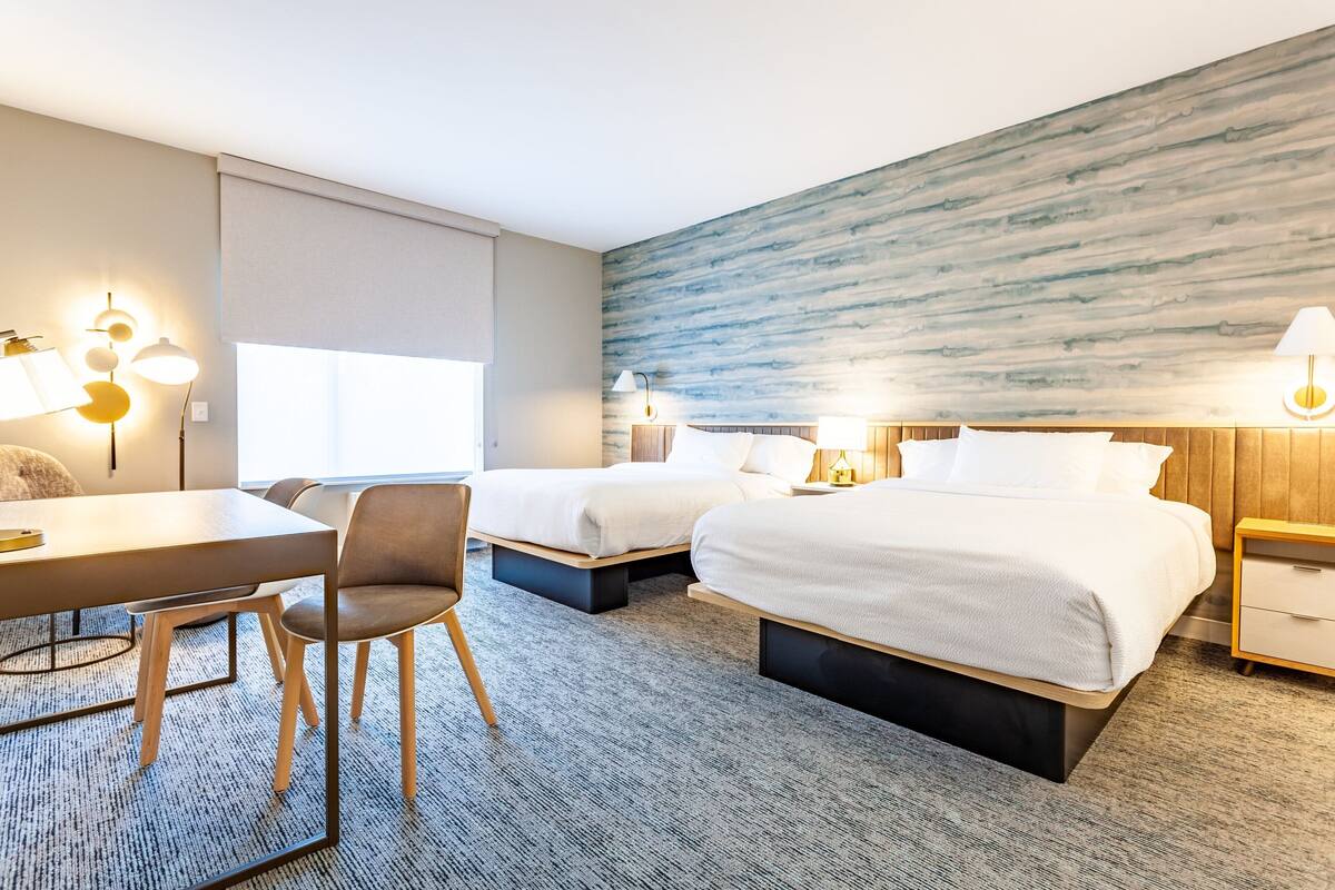Ein Hotelzimmer mit zwei Betten, einem Schreibtisch und einem Stuhl.