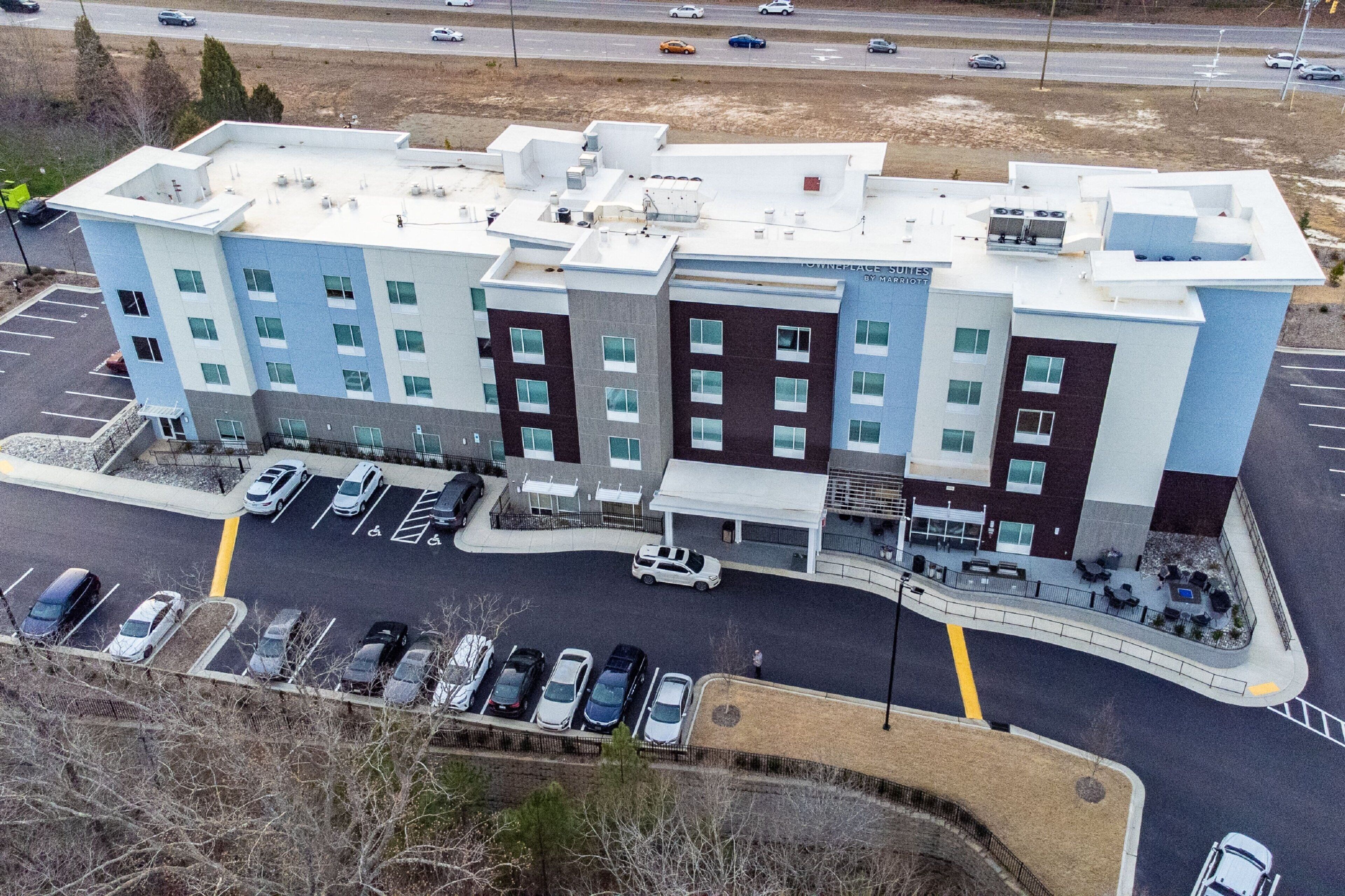 A multi-story hotel with a parking lot and a road in the background.