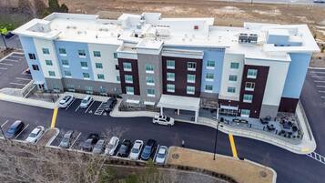A multi-story hotel with a parking lot and a road in the background.