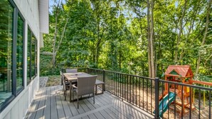 A wooden deck with a table and chairs, surrounded by a metal railing. - High-End Modern Farmhouse Relaxation in Saugatuck - Close to Downtown (Saugatuck)
