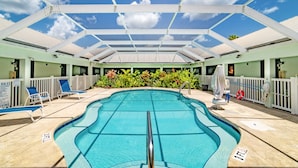 An indoor swimming pool with a glass ceiling, surrounded by lounge chairs and a white fence. - Everglades Adventures Hotel Suites by Ivey House (Everglades City)