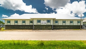 A hotel with a flat roof, a sign indicating hotel suites, and a fenced parking area. - Everglades Adventures Hotel Suites by Ivey House (Everglades City)