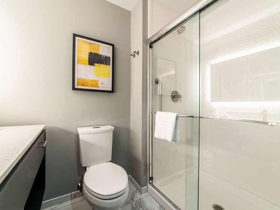 A modern bathroom with a glass shower enclosure, a toilet, and a marble floor.