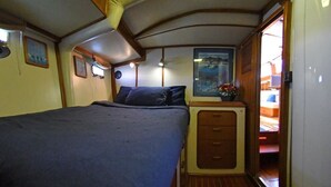 A compact bedroom with a bed, a small dresser, and a window with a view. - Beautiful 72 foot sailing yacht. Explore the Sea of Cortez in style.  (La Paz)
