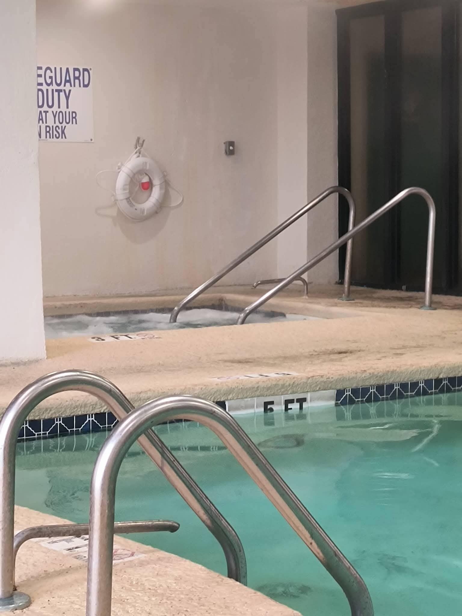 En swimmingpool med stålvægge, et livredder skilt og et område med jacuzzi.
