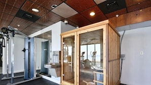 Een fitnessruimte met trainingsapparatuur, een waterfontein en een sauna.