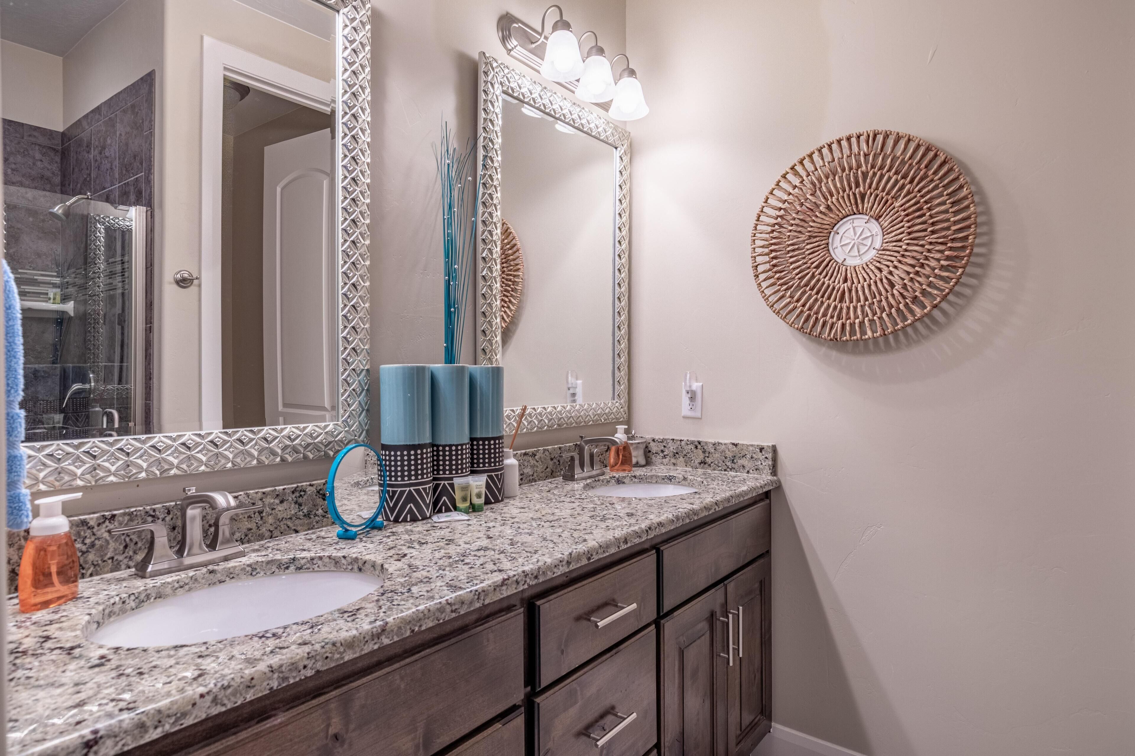 A bathroom with two sinks, a mirror, and a wall-mounted light fixture.