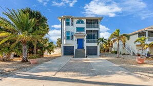 A two-story house with a blue door, a balcony, and a driveway leading to the entrance.