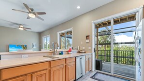 A kitchen with wooden cabinets, a dishwasher, a large island, and a sliding glass door to a deck.