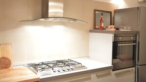 Une cuisine moderne équipée d’une cuisinière à gaz, d’appareils électroménagers en acier inoxydable et d’une hotte en verre.