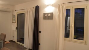 Une chambre d’hôtel avec une porte-fenêtre coulissante, une petite table et une chaise.