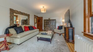 A living room with a sofa, armchairs, a coffee table, a side table, a mirror, a cabinet, a television, and a radiator. - Downtown Delight off Pearl street (Boulder)