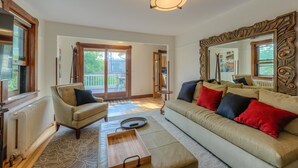 A living room with a sofa, armchairs, a coffee table, and a large mirror. - Downtown Delight off Pearl street (Boulder)