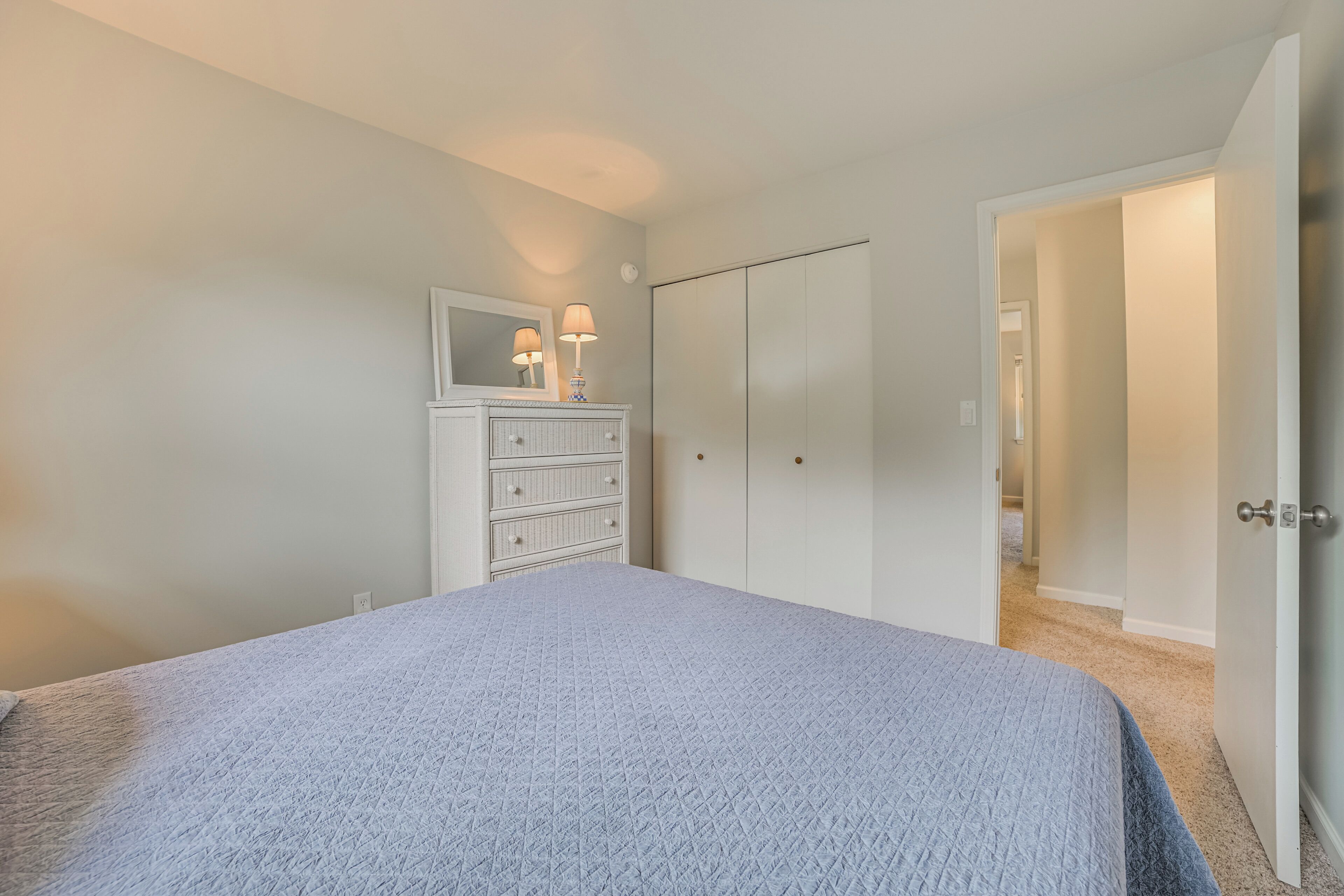 Ein Schlafzimmer mit Bett, Kommode mit Spiegel und Kleiderschrank.