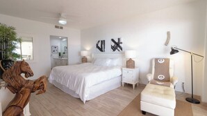 Une chambre à coucher avec un grand lit, des lampes de chevet, une chaise, une lampe sur pied et une sculpture équestre en bois.