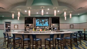 A bar area with a long counter, multiple bar stools, and a large screen displaying an underwater scene.