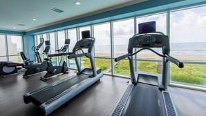 Ett gym med löpband, motionscyklar och crosstrainers, stora fönster med utsikt över havet.