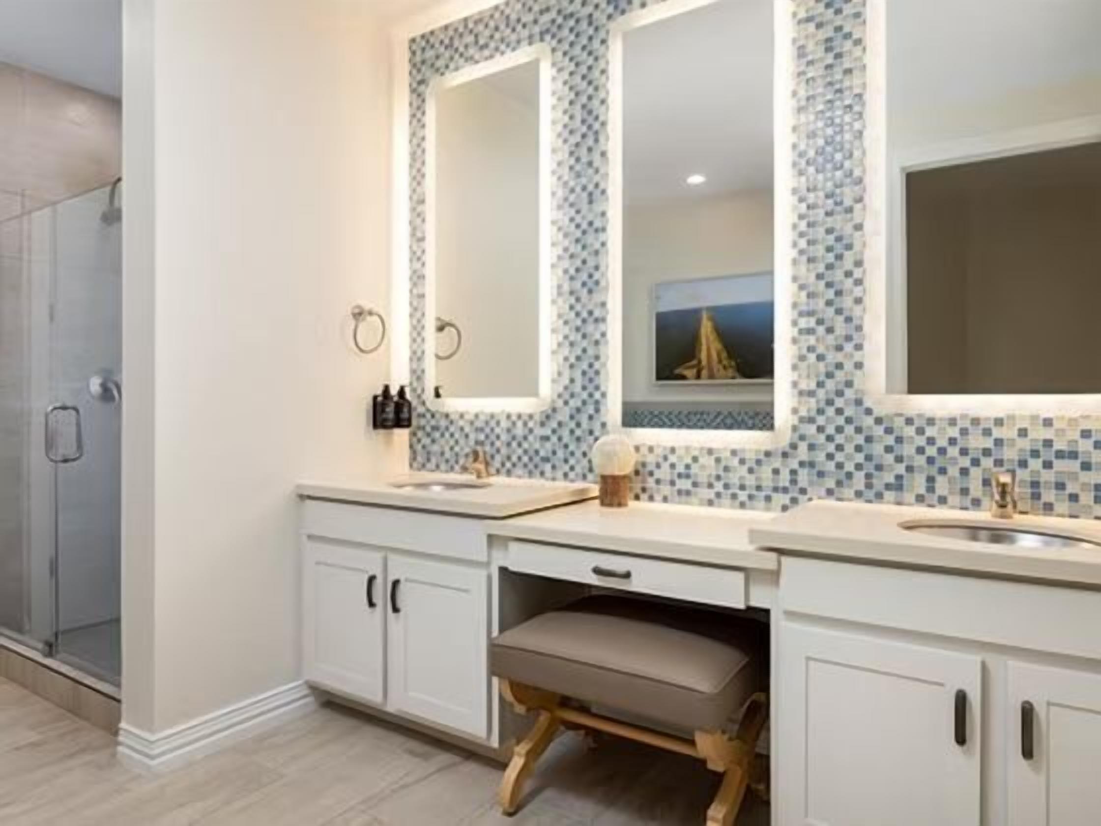 Un baño con dos lavamanos, un espejo grande y una cabina de ducha.