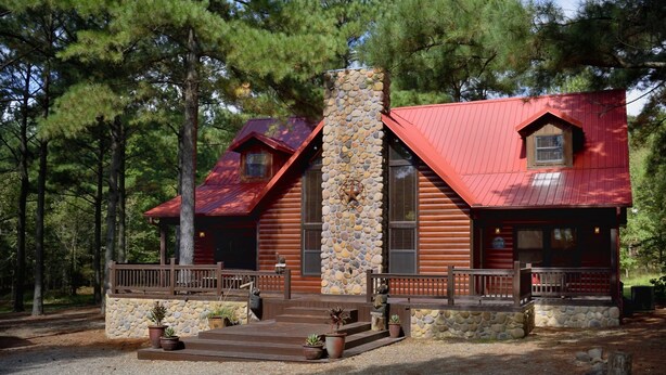 A log cabin with a stone chimney, a porch with railings, and a small window. - Rowdy Rooster, A Relaxing Cabin 3.4 miles from nearest Broken Bow Lake boat ramp (Broken Bow)