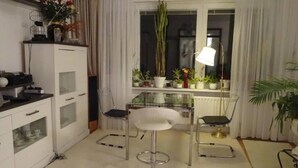 A compact kitchen with a glass-top table, two bar stools, and a window with curtains. - Beautiful, quiet apartment in the countryside in Berlin-Steglitz (Berlin)