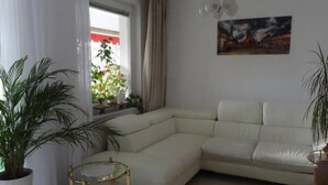 A living room with a white sofa, a small round table, and a potted plant. - Beautiful, quiet apartment in the countryside in Berlin-Steglitz (Berlin)