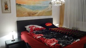 A bedroom with a bed, a nightstand, a painting, and a chandelier. - Beautiful, quiet apartment in the countryside in Berlin-Steglitz (Berlin)