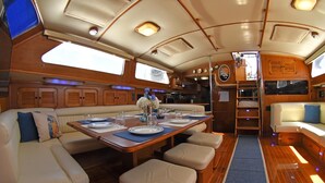 A yacht interior with a dining area, seating, and a kitchen. - The ultimate sailing yacht vacation in the Sea of Cortez. Jersey Girl II  (La Paz)