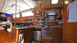 A compact galley with a sink, microwave, stove, and storage cabinets. - The ultimate sailing yacht vacation in the Sea of Cortez. Jersey Girl II  (La Paz)