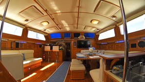 A boat interior with a dining area, seating, and a small kitchen. - The ultimate sailing yacht vacation in the Sea of Cortez. Jersey Girl II  (La Paz)