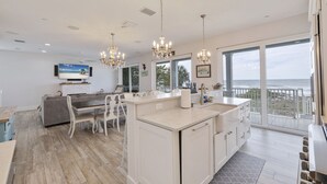 A modern kitchen with a large island, white cabinetry, and a view of the ocean.