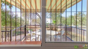 A balcony with a striped awning, white plastic chairs, and a table. - Private Holiday Home in the Countryside (Alhaurín el Grande)