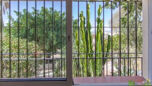 A window with metal bars, a view of green cacti and trees, and a clear sky. - Private Holiday Home in the Countryside (Alhaurín el Grande)