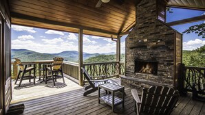 A wooden deck with outdoor seating, a stone fireplace, and a scenic mountain view. - A View  To Remember (Morganton)