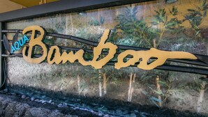 A sign with the word "Bamboo" and the word "Aqua" above it, with a background of a forest scene. - 10th Floor Air Conditioned Apt in Central -Bamboo Waikiki 1005 (Honolulu)