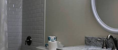 Ein Badezimmer mit Dusche, Toilette, Waschbecken und Spiegel.
