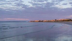 A beach with a row of buildings in the background. - Top Floor, Partial Oceanview, Peaceful Condo (St. Simons)
