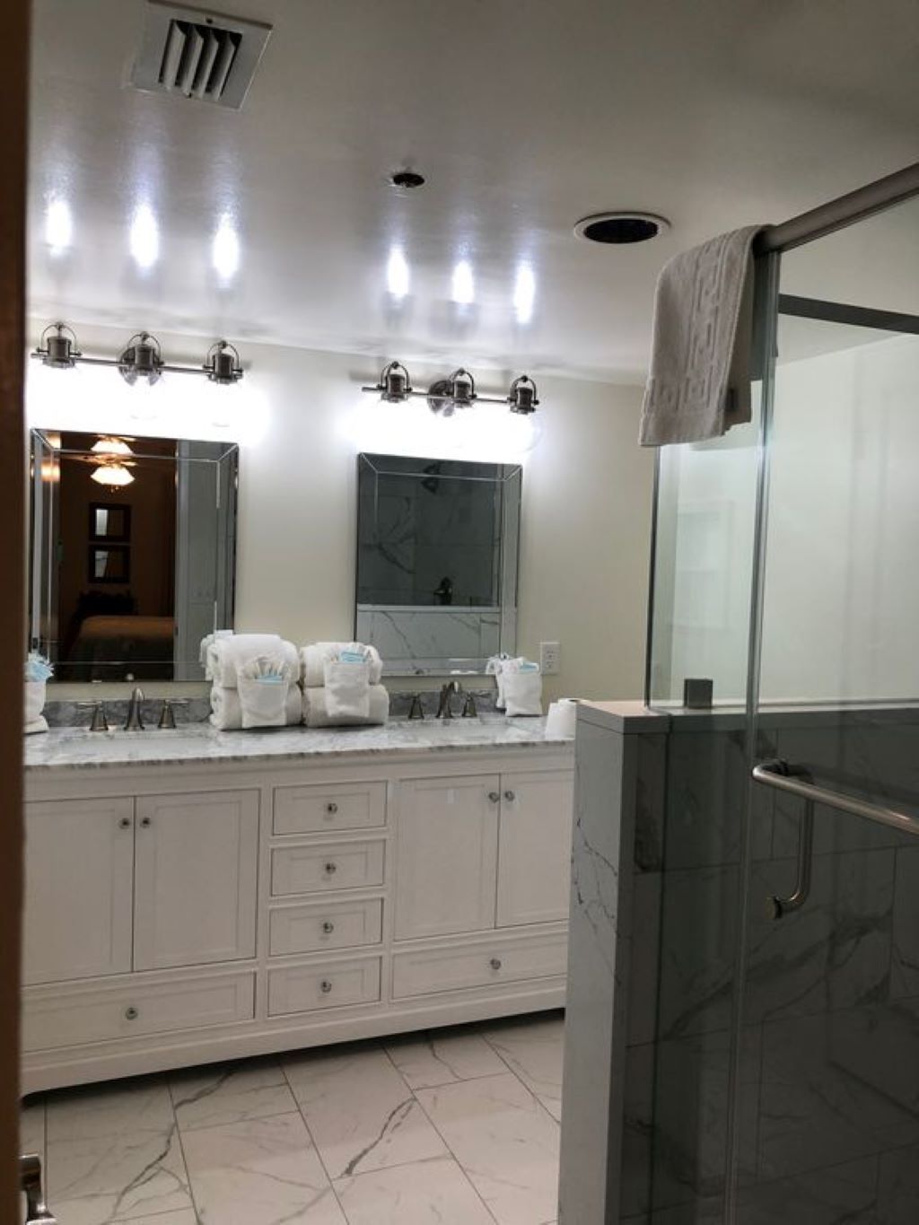 A modern bathroom with a large vanity, a glass shower enclosure, and multiple overhead lights.