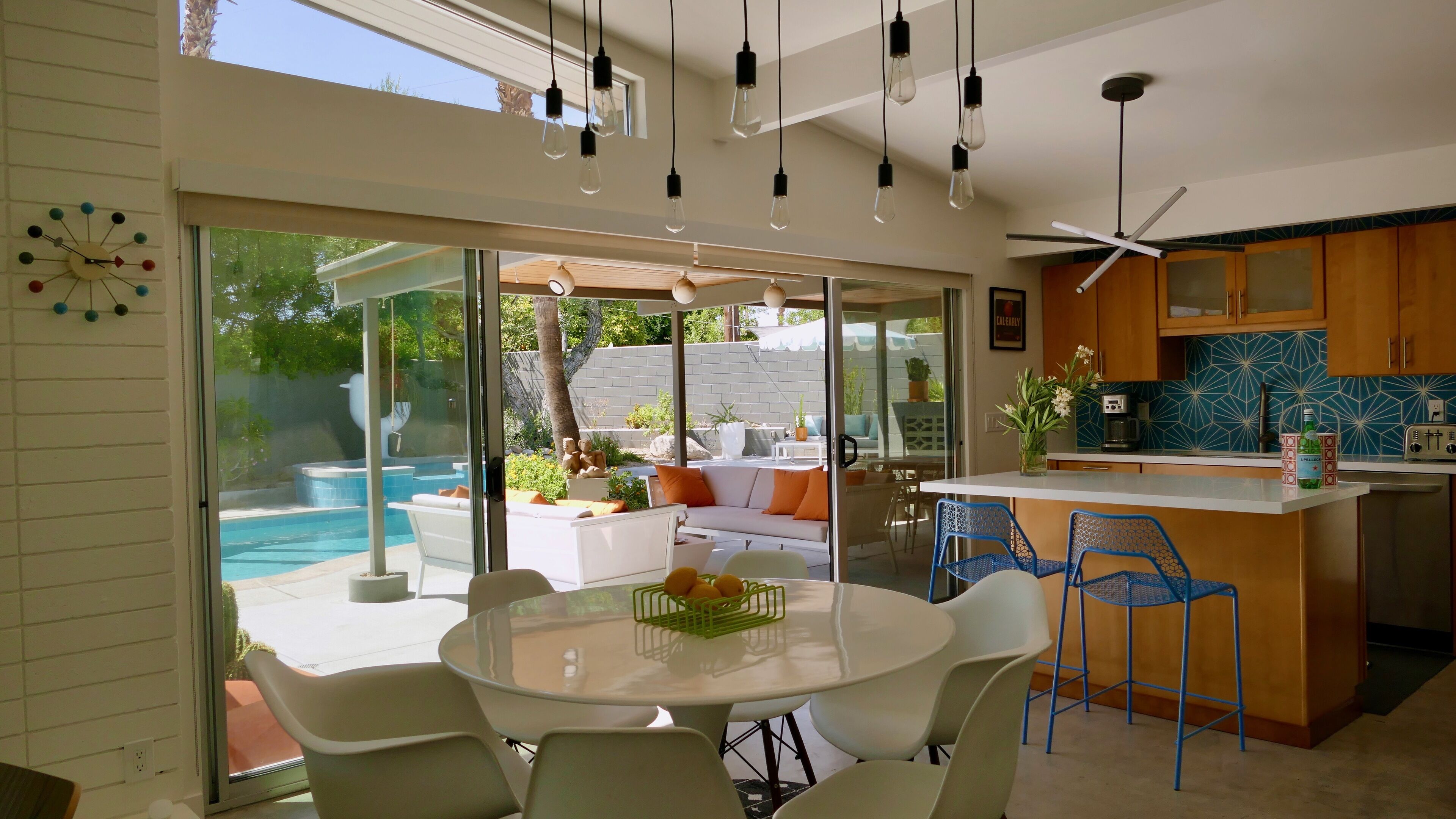 A modern kitchen with a blue tiled backsplash, a white countertop, and a ceiling fan.