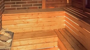 Banco de sauna de madera con pared de ladrillo y paneles de madera al fondo.