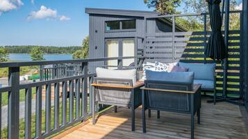 Une terrasse en bois avec des meubles d’extérieur, un petit bâtiment et une vue sur un lac.