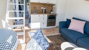 Un espacio habitable compacto con kitchenette, un sofá, una mesa de comedor y una escalera.