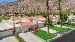 A residential area with houses featuring red-tiled roofs, surrounded by palm trees and a mountain backdrop. - Golf Course Retreat w/ Private Casita Steps to La Quinta Resort & Pools (La Quinta)