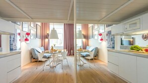 A modern kitchen with white cabinetry, a dining area with a round table and chairs, and pendant lighting. - Tromostovje III at Triple Bridge Ljubljana, Ljubljana, Slovenia (Ljubljana)